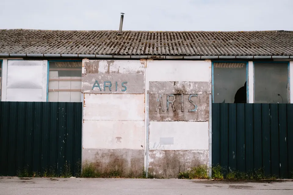 Bâtiment désaffecté couvert de plaques ondulées grises, surmonté d'un petit conduit